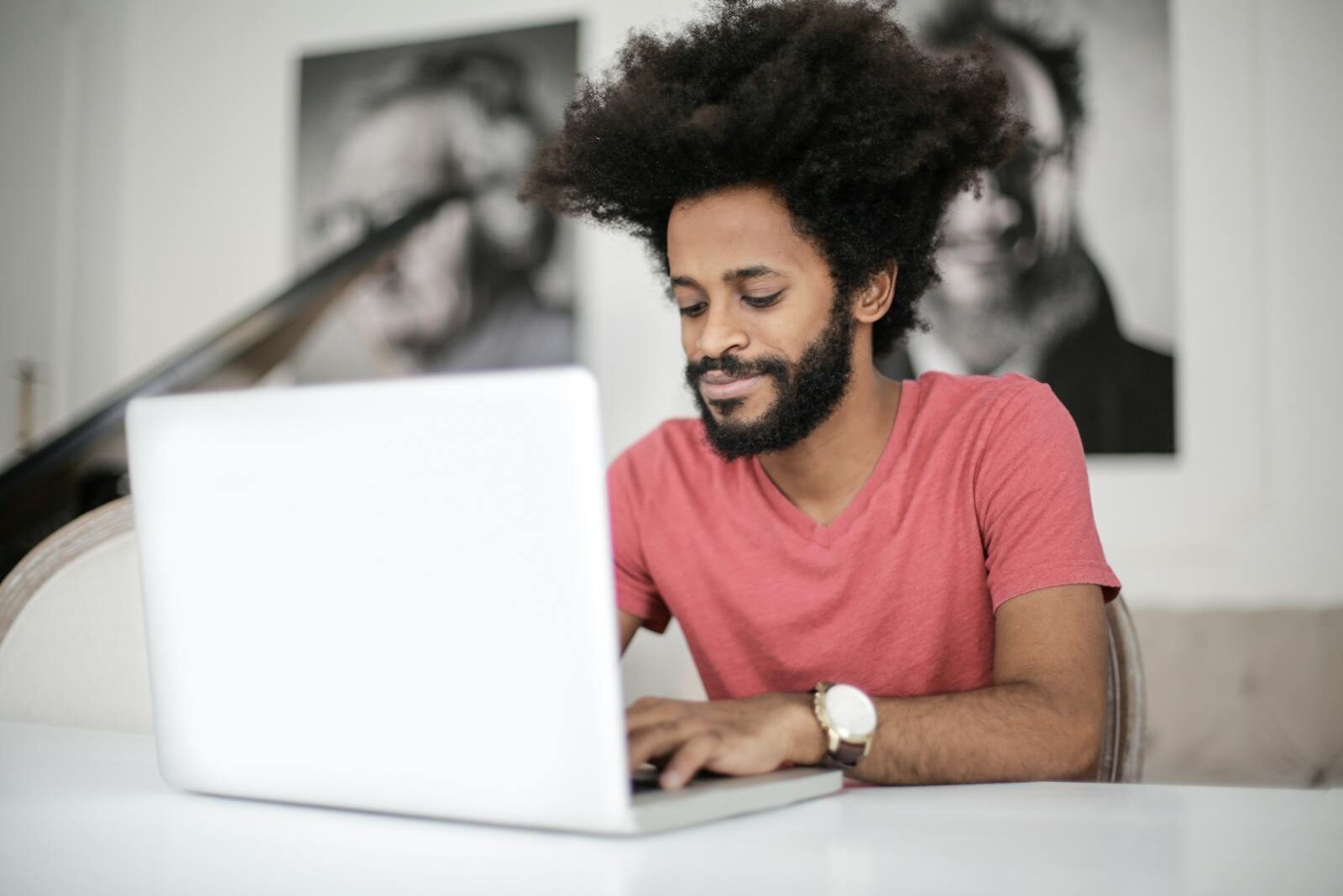 A man with afro hair works on his laptop at a desk, symbolizing modern remote work and freelance lifestyle.