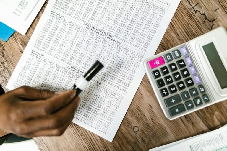 Close-up of tax documents and calculator on wooden table, highlighting financial analysis.
